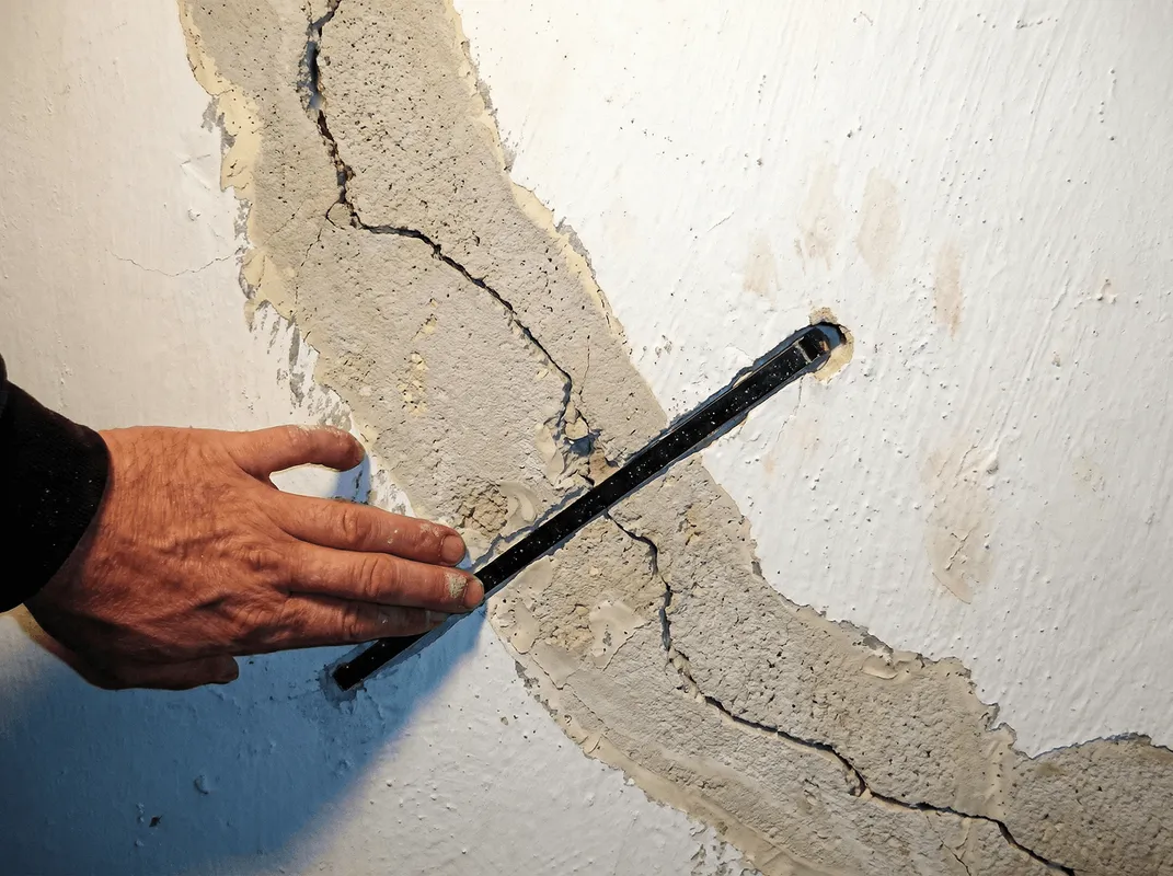 A wall with a large crack is being inspected by a professional in Gilbert, AZ